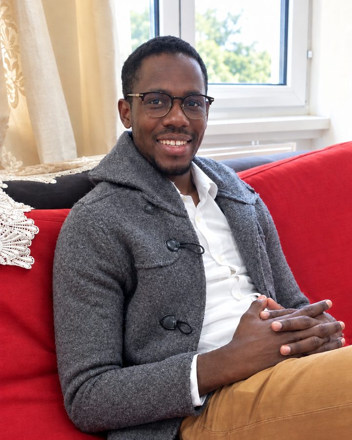 Gora Kebe, souriant, assis sur un canapé rouge